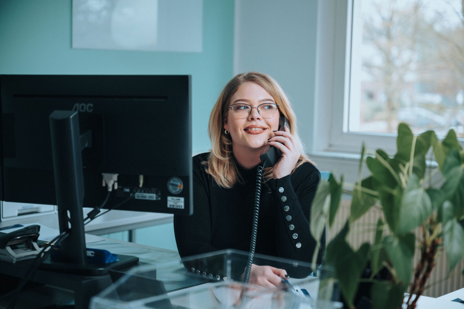 Porträt einer lächelnden Kundenberaterin von ACS mit Telefonhörer am Ohr